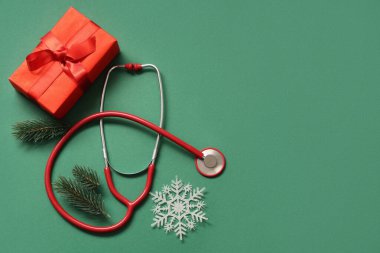 Hediye kutulu steteskop ve yeşil arka planda Noel ağacı dalları