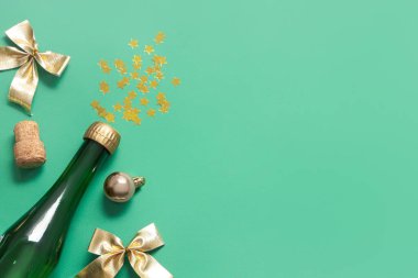 Bir şişe mantarlı şampanya ve yeşil arka planda Noel dekoru.