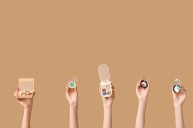 Kahverengi arka planda farklı göz falı paletleri olan kadın elleri