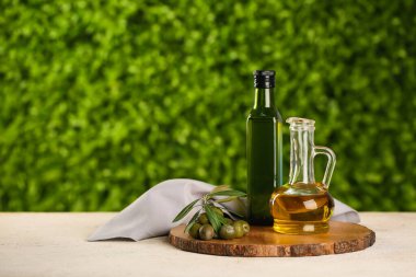 Dekan ve bir şişe taze zeytinyağı açık havada beyaz masada.