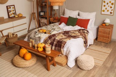 Sonbahar süslemeleri ve mumları olan şık bir yatak odası.