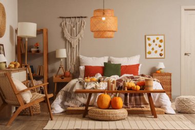 Sonbahar süslemeleri ve mumları olan şık bir yatak odası.