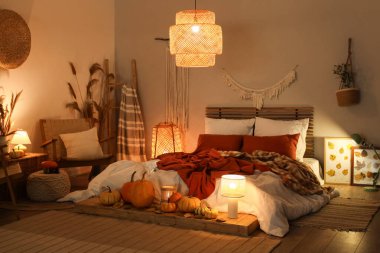 Sonbahar süslemeleri ve akşamları mumları olan şık bir yatak odası.