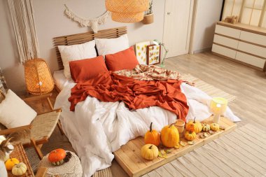 Sonbahar süslemeleri ve büyük yataklı şık bir yatak odası.