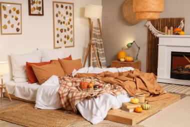 Sonbahar süslemeleri ve şömineli mumları olan şık bir yatak odası.