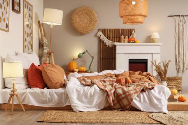 Sonbahar süslemeleri ve şömineli mumları olan şık bir yatak odası.