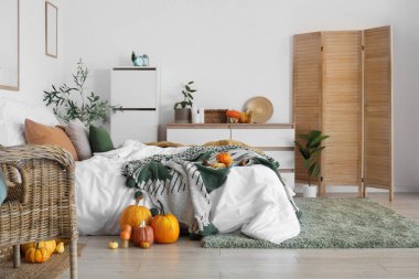 Çekmeceleri, perdesi ve balkabakları olan hafif yatak odasının içi.