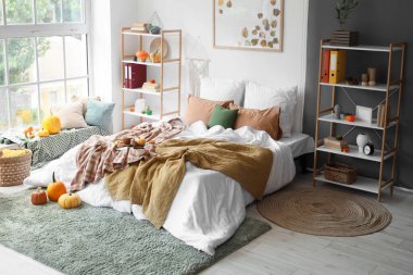 Yatak odasının içinde raf üniteleri ve balkabakları var.