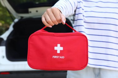 Arabanın yanında ilk yardım çantası olan bir sürücü.