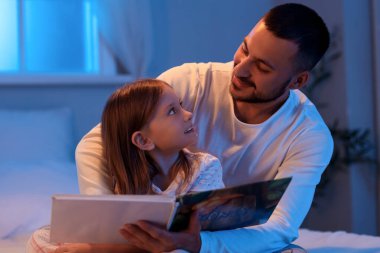Baba ve küçük kızı evde masal okuyorlar.