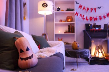 Cadılar Bayramı balkabağı gri kanepede, karanlık oturma odasında, yakın plan