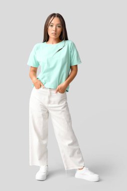 Gri arka planda zarif nane makyajlı şık Asyalı bir kadın.