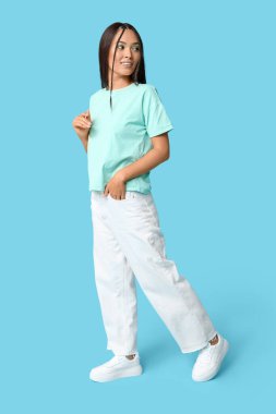 Mavi arka planda güzel nane makyajlı şık genç Asyalı kadın.