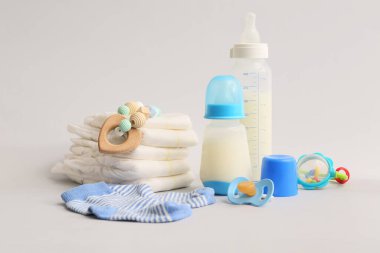 Bebek sütü formüllü şişeler, bebek bezleri, çoraplar ve hafif arka planda aksesuarlar.