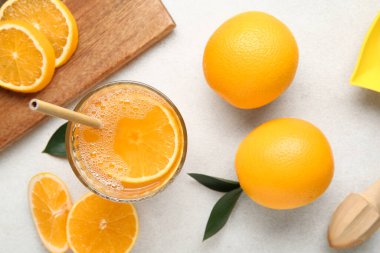 Bir bardak lezzetli meyve suyu ve beyaz arka planda taze portakallar.