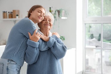 Mutlu son sınıf öğrencisi kadın ve torunu mutfakta sarılıyorlar.