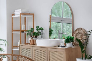 Modern lavabosu, aynası ve raf ünitesi olan bir banyo.