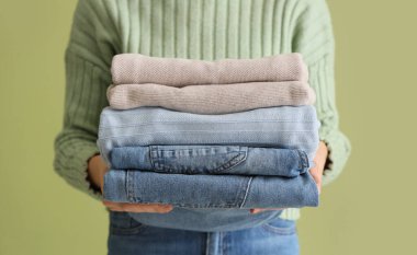 Yeşil arka planda şık kıyafetleri olan genç bir kadın, yakın plan.