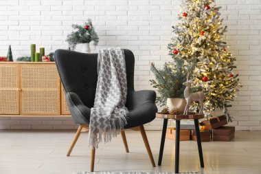 Koltuklu ve ışıldayan Noel ağacı olan oturma odasının içinde.