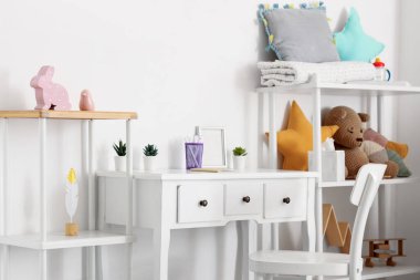 Masası, raf ünitesi ve oyuncakları olan çocuk odasının içi