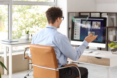 Bilgisayarlı genç iş adamı ofiste görüntülü sohbet ediyor.