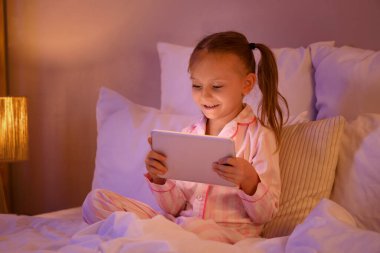 Tabletli, tatlı, mutlu bir kız. Akşamları evde oyun oynuyor.