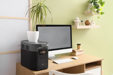 Ofisteki yeşil duvarın yanında santral ve bilgisayarı olan taşınabilir elektrik santrali.