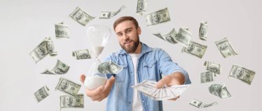 Kum saati ve hafif arka planda parası olan genç bir adam.