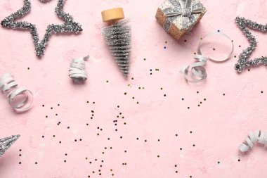 Hediye kutusu ve pembe arka planda Noel dekoru olan kompozisyon