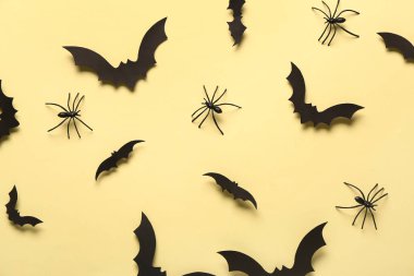 Cadılar Bayramı partisi için sarı arka planda kağıt yarasalar ve örümcekler.