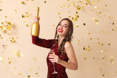 Şampanya içen ve bej arka planda konfeti düşen genç bir kadın. Yeni yıl kutlaması