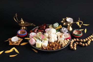 Siyah zemin üzerinde mumlar, boncuklar ve farklı tabaklar bulunan Diya lambaları. Divaly kutlaması