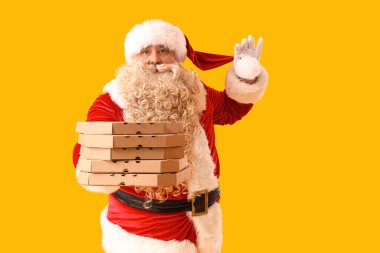 Sarı arka planda pizza kutuları olan Noel Baba.