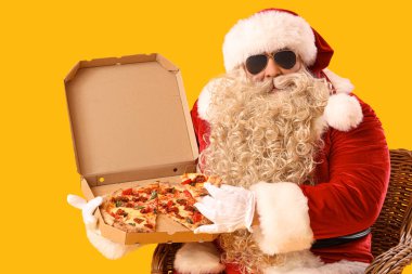 Havalı Noel Baba, sarı arka planda koltukta lezzetli pizzalar.