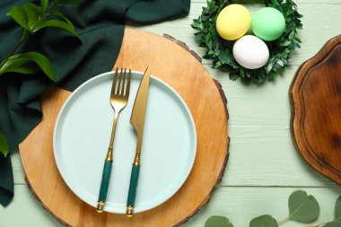 Paskalya için güzel bir masa, yumurta, çelenk ve ahşap arka planda yeşil dallar.