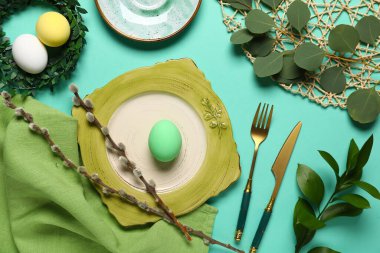 Yumurta, çelenk ve turkuaz arka planda yeşil dallarla Paskalya için güzel bir masa.