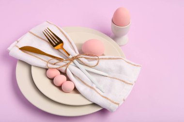 Leylak arka planında pembe Paskalya yumurtaları olan güzel bir masa.