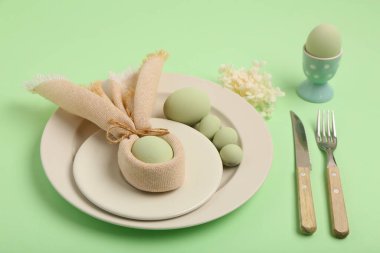 Yeşil arka planda Paskalya yumurtaları ve güzel çiçekleri olan masa ayarı