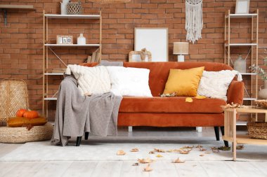 Oturma odasının sonbaharında rahat bir kanepe, sehpa ve dağınık yapraklarla dolu.