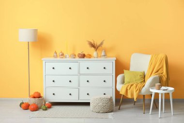 Beyaz koltuklu, kahve masalı ve çekmeceli bir sonbahar salonu.