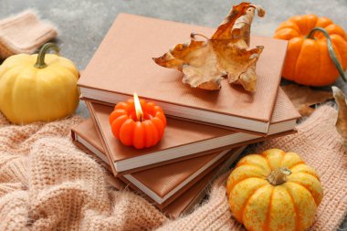 Bir yığın kitap, süveter, mum ve sonbahar yapraklı kompozisyon grunge arka planda, yakın plan