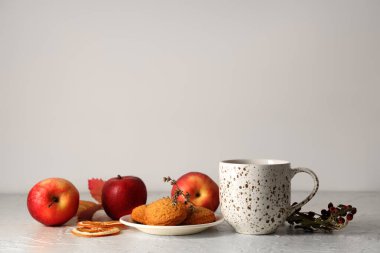 Beyaz duvarın yanındaki masada yeşil çay, elma ve kurabiye karışımı.