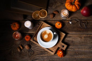 Balkabaklarıyla, elmalarıyla, portakallarıyla, kitaplarıyla ve kahve fincanlarıyla yanan mumlar.