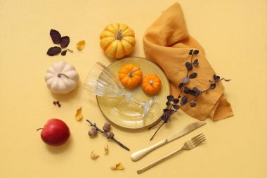 Taze balkabakları, elmaları, meşe palamutları, dalları ve sarı arka planda sonbahar yaprakları olan güzel masa ortamları.