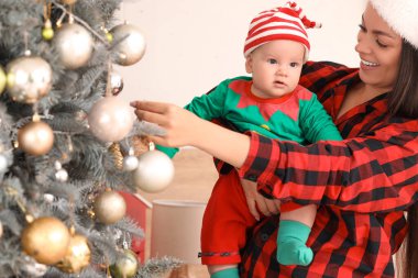 Anne ve küçük bebeği yatak odasındaki Noel ağacının yanında elf gibi giyinmiş.