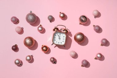 Pembe arka planda çalar saat ve Noel topları. Üst görünüm