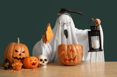 Ahşap masada oyulmuş Cadılar Bayramı balkabakları ve feneri olan bir hayalet.