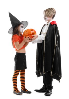 Cadılar Bayramı için giyinmiş küçük çocuklar ve beyaz arka planda balkabağı.