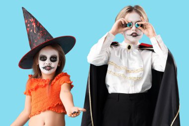 Cadılar Bayramı için giyinmiş küçük çocuklar mavi arka planda