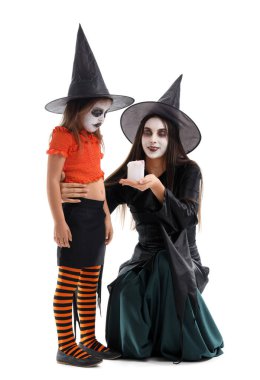 Annesiyle Cadılar Bayramı için beyaz arka planda giyinmiş küçük bir kız.